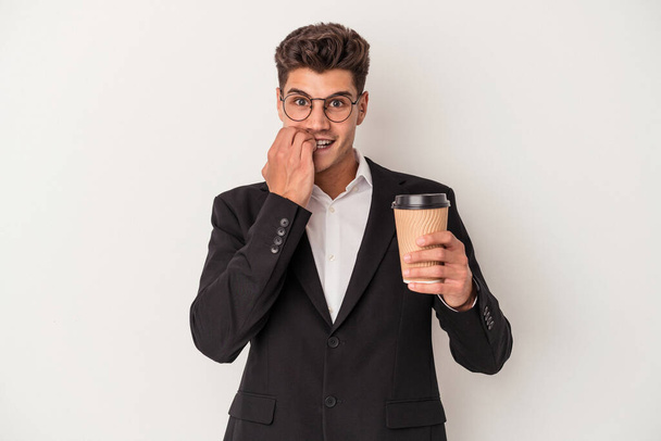 Young business caucasian man holding take away coffee isolated on white background biting fingernails, nervous and very anxious. - Zdjęcie, obraz