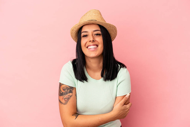 Young caucasian woman with one arm wearing a summer hat isolated on pink background laughing and having fun. - Photo, Image