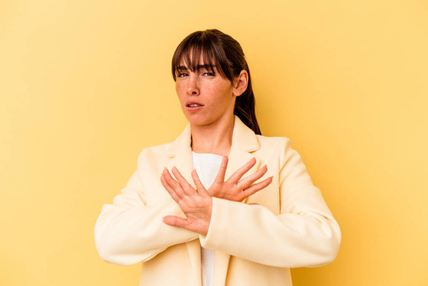 Young Argentinian woman isolated on yellow background doing a denial gesture - Фото, изображение