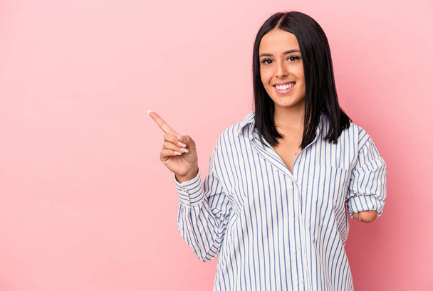 Young caucasian woman with one arm isolated on pink background smiling and pointing aside, showing something at blank space. - Foto, Imagen