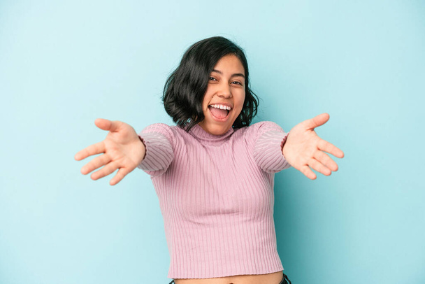 Young latin woman isolated on blue background feels confident giving a hug to the camera. - Foto, imagen