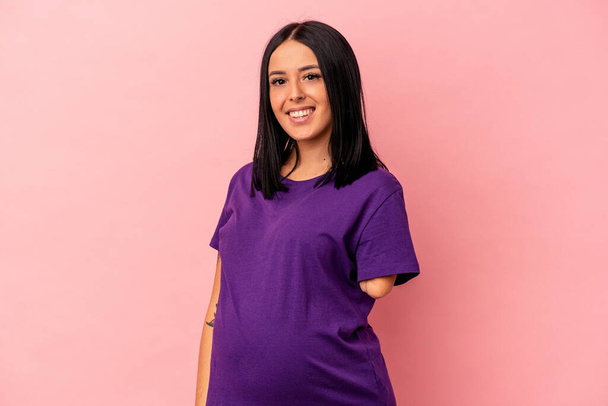 Young pregnant woman with one arm isolated on pink background happy, smiling and cheerful. - Photo, Image