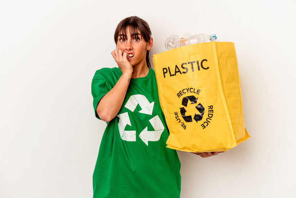 Junge Argentinierin recycelt Kunststoff isoliert auf weißem Hintergrund beißt Fingernägel, nervös und sehr ängstlich. - Foto, Bild