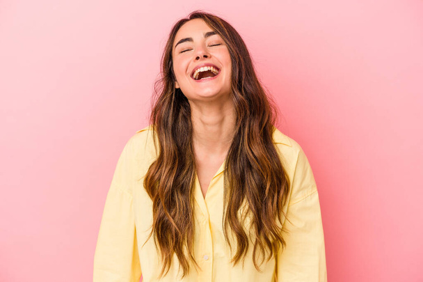 Jeune femme caucasienne isolée sur fond rose détendue et heureuse en riant, le cou tendu montrant les dents. - Photo, image