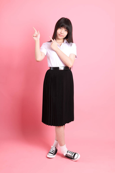 The teen Asian girl with university uniform standing on the pink background. - Photo, Image