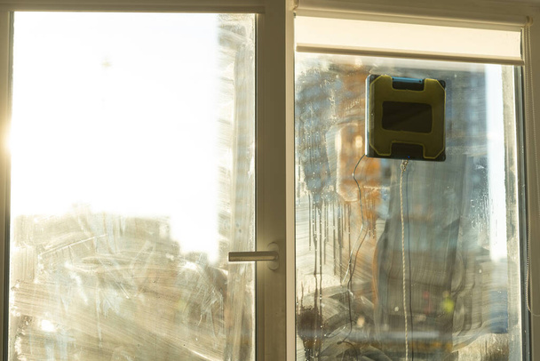 Robot cam temizleyicisi kirli camlarda çalışır. Evi akıllı aletlerle temizlemek. Pencereleri temizlemek için otomatik vakumlu robotlar, ev için bir asistan - Fotoğraf, Görsel