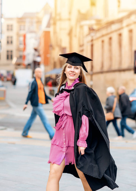 cuarenta - año - anciana mujer feliz en vestido de graduación caminando por el centro de la ciudad. Estudiar a cualquier edad - Foto, Imagen