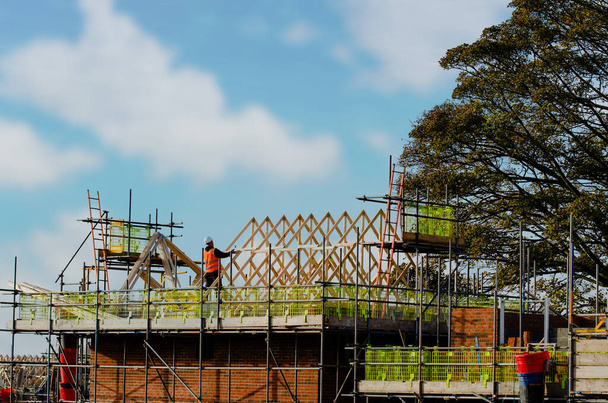 Trabajador de construcción colocando viguetas de techo para posicionarlas y fijarlas en la nueva construcción de techos residenciales - Foto, Imagen