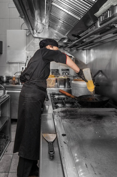 Sivunäkymä naiskokki työskentelee kaupallisessa keittiössä - Valokuva, kuva