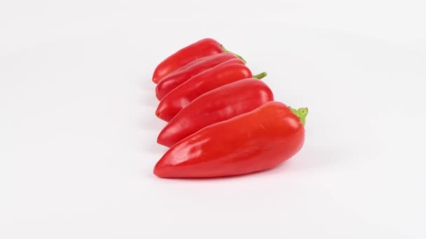 Pět červených sladkých paprik na bílém pozadí. Paprika se řadí od nejmenšího po největší. Pohyb smyčky. Boční pohled. Rotace 360. Videozáznam 4K UHD 3840X2160. - Záběry, video