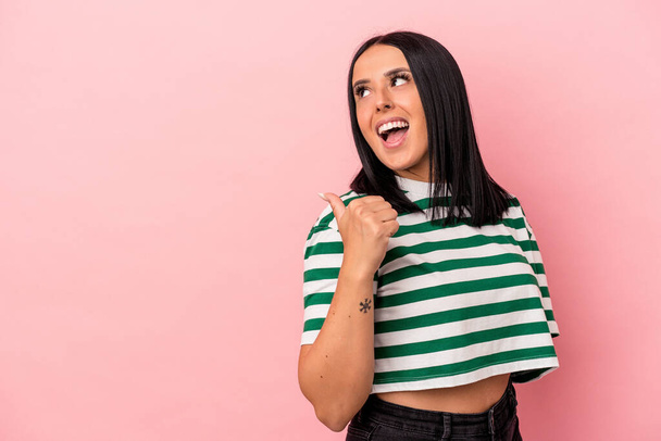Young caucasian woman with one arm isolated on pink background points with thumb finger away, laughing and carefree. - 写真・画像