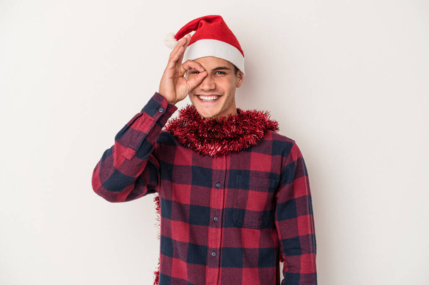 Young caucasian man celebrating Christmas isolated on white background excited keeping ok gesture on eye. - Fotoğraf, Görsel
