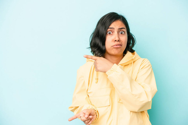 Young latin woman isolated on blue background shocked pointing with index fingers to a copy space. - Photo, Image