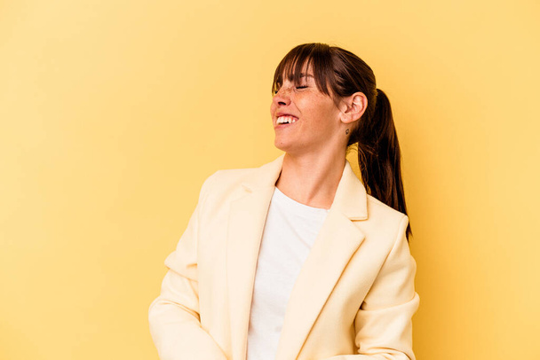 Young Argentinian woman isolated on yellow background relaxed and happy laughing, neck stretched showing teeth. - Fotó, kép