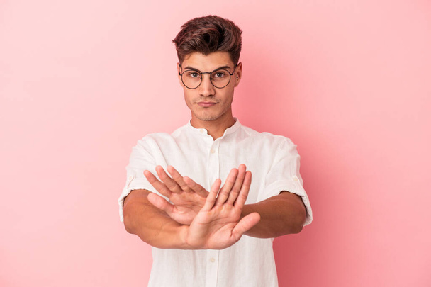 Jonge blanke man geïsoleerd op roze achtergrond staan met uitgestrekte hand tonen stopteken, voorkomen dat u. - Foto, afbeelding