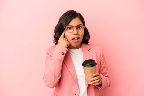 Giovane donna latina in possesso di take away caffè isolato su sfondo rosa mostrando un gesto di delusione con indice. - Foto, immagini