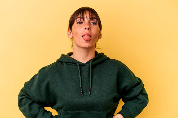 Young Argentinian woman isolated on yellow background funny and friendly sticking out tongue. - Foto, Imagen