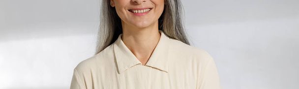 Portret van mooie grijsharige vrouw in beige blouse op lichte achtergrond - Foto, afbeelding
