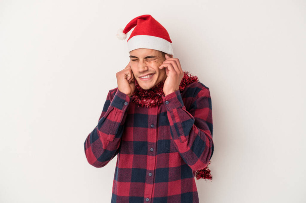 Молодой кавказский человек празднующий Рождество изолирован на белом фоне закрывая уши руками. - Фото, изображение