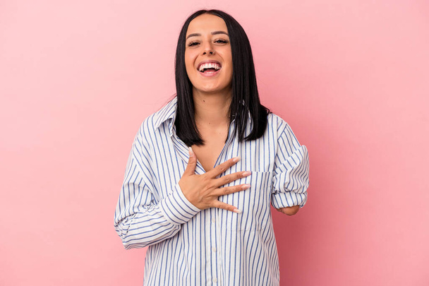 Young caucasian woman with one arm isolated on pink background laughs out loudly keeping hand on chest. - Photo, Image