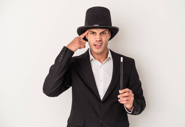 Young magician caucasian man holding a wand isolated on white background showing a disappointment gesture with forefinger. - Foto, Bild