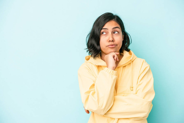 Young latin woman isolated on blue background looking sideways with doubtful and skeptical expression. - Photo, Image