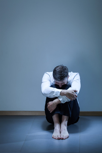 Депрессивный молодой бизнесмен, сидящий на полу
 - Фото, изображение
