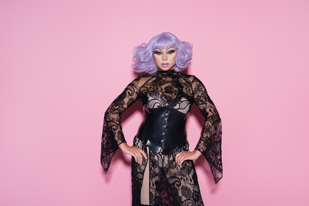 eccentric drag queen in purple wig and black lace dress looking at camera on pink - Fotoğraf, Görsel