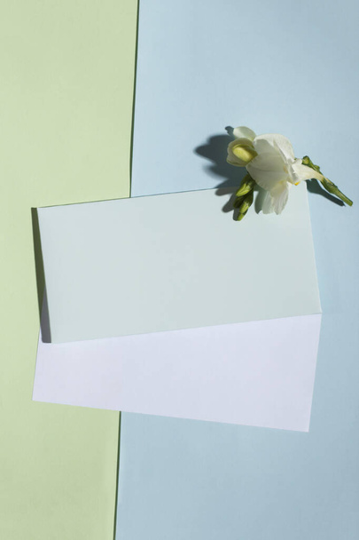 Πρόσκληση ή ευχετήρια κάρτα mockup με φάκελο και λευκό χαρτί σε παστέλ πράσινο και μπλε φόντο. Κομψό μακιγιάρισμα πάνω όψης με χώρο αντιγραφής. Πρότυπο για το branding και τη διαφήμιση - Φωτογραφία, εικόνα