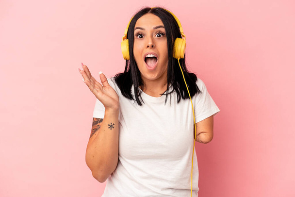 Young caucasian woman with one arm listening to music isolated on pink background surprised and shocked. - Фото, зображення