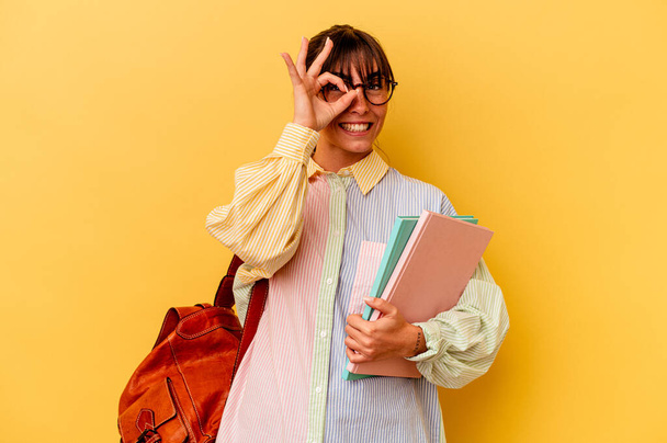 Young student Argentinian woman isolated on yellow background excited keeping ok gesture on eye. - Φωτογραφία, εικόνα