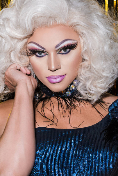 πορτρέτο της drag queen σε ξανθιά περούκα και φωτεινό μακιγιάζ κοιτάζοντας κάμερα - Φωτογραφία, εικόνα