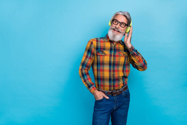 Photo of dreamy man dressed checkered shirt glasses listening music empty space isolated blue color background - Fotoğraf, Görsel