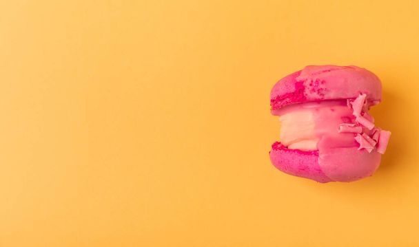 Köstliche Beerenmakronen auf weichem gelb-orangefarbenem Papier. Französische Baiser-Macarons. Kulinarisches Konzept. Kopierraum. Blick von oben. - Foto, Bild