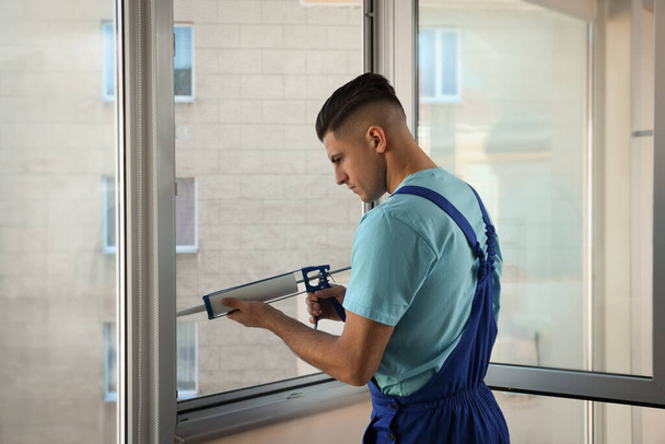 Construction worker sealing window with caulk indoors - Zdjęcie, obraz