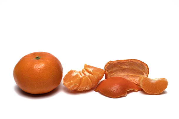 Закрыть спелый мандарин рядом с кожурой и очистить половину с ломтиком на белом фоне - Фото, изображение
