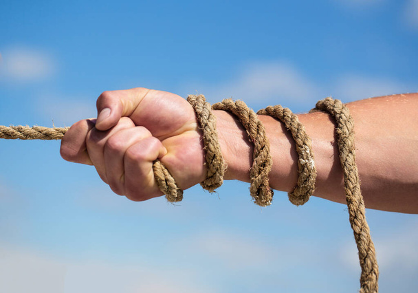 Helping hand, arm, friendship. Rope, cord. Hand holding a rope, climbing rope, strength and determination. Rescue, help, helping gesture or hands. Conflict tug of war - Photo, Image