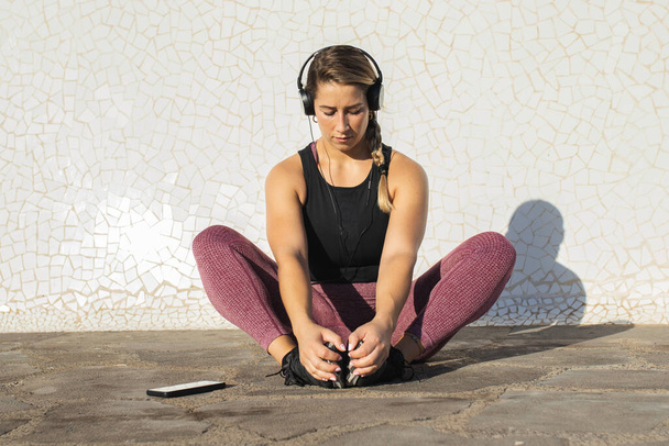 jonge vrouw stretching tijdens het luisteren naar muziek - Foto, afbeelding