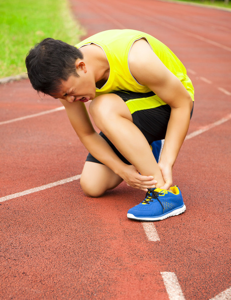 young male runner with ankle injury on track - Foto, Imagem