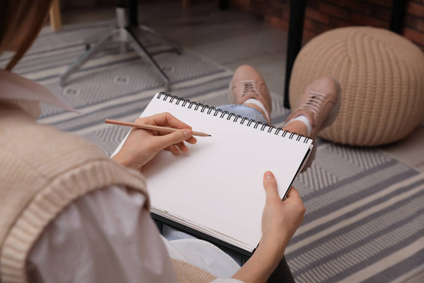 Nainen piirtää luonnosvihkoon lyijykynällä kotona, lähikuva - Valokuva, kuva