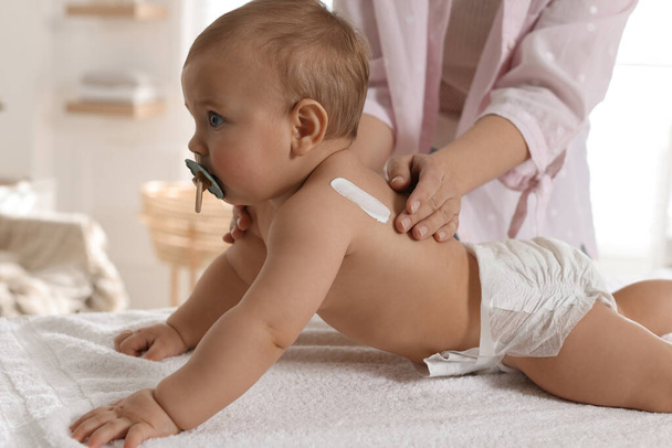 Mother applying body cream on her little baby at home, closeup - Fotó, kép