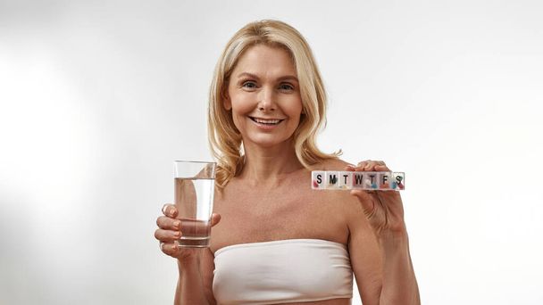 Woman showing glass with water and set with pills - Foto, imagen