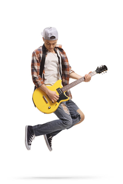 Male teenager jumping and playing an electric guitar isolated on white background - Foto, Bild