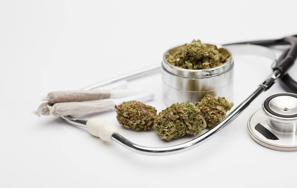 brotes de marihuana, articulación, molinillo, fonendoscopio, con fondo blanco. - Foto, imagen