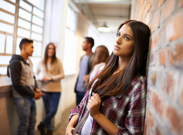 Люблю життя в кампусі. Знімок красивої молодої студентки, яка виглядає нудно, спираючись на цегляну стіну в кампусі
. - Фото, зображення