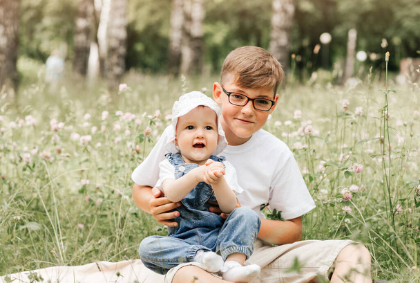 garçon en lunettes avec bébé soeur dans un cadre extérieur - Photo, image