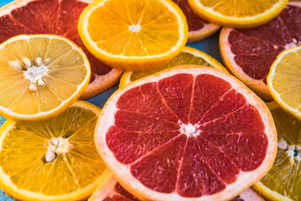 Slices, pieces, whole ripe citruses are on background. Juicy tangerines, oranges, grapefruits, lemons, limes, leaves are on yellow canvas. Summer exotic tropical citrus fruits for preparing juice. - 写真・画像