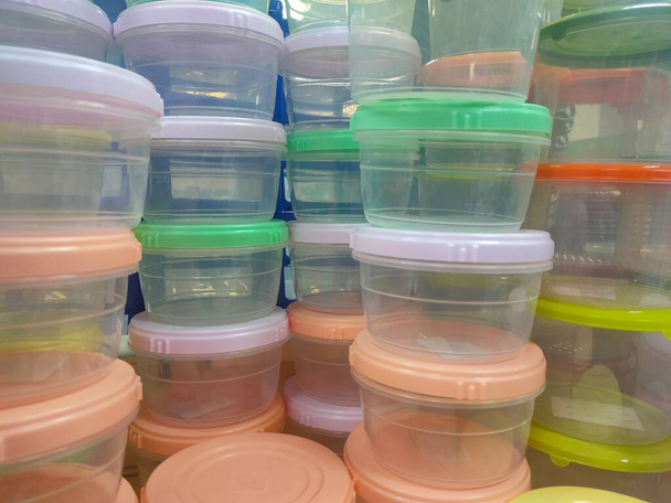 многоразовые контейнеры из пищевого пластика с разноцветными крышками на стойке магазина - Фото, изображение