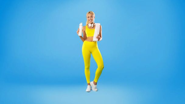 Desportivo sorrindo mulher posando no estúdio com garrafa de água - Foto, Imagem