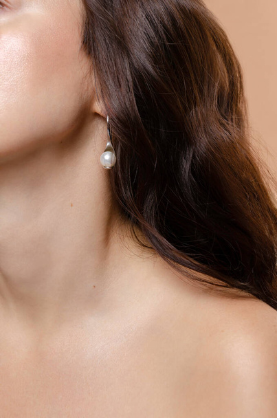 Vrouw studio schoonheid portret close-up met parel oorbellen sieraden. Gloeiende natuurlijke huid, huidverzorging, UV-zonwering.  - Foto, afbeelding